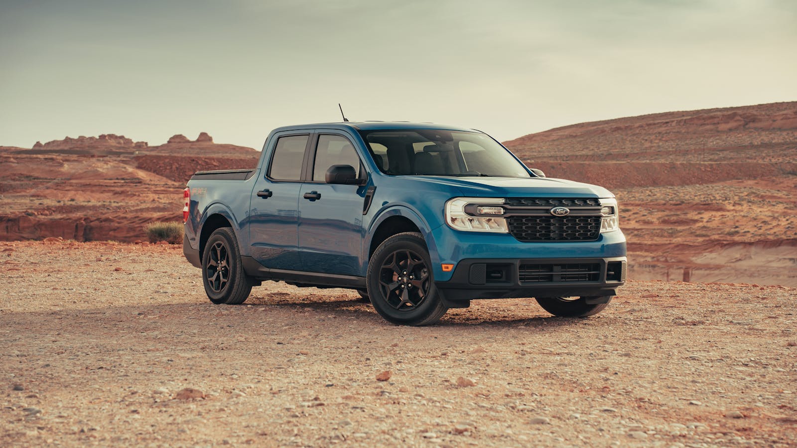 A blue Ford Maverick pickup truck in a serene desert landscape near Page, Arizona.